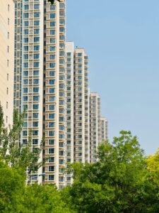 Tall residential buildings with green foliage and blue sky in an urban area.